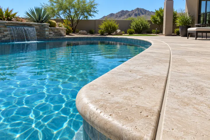 Fresh tan travertine pool coping with a rounded bullnose edge and a clean expansion joint between coping and deck