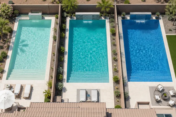 Three pool water colors side by side in neighboring backyard pools: pale aqua, turquoise and medium blue, aerial view of plaster finishes